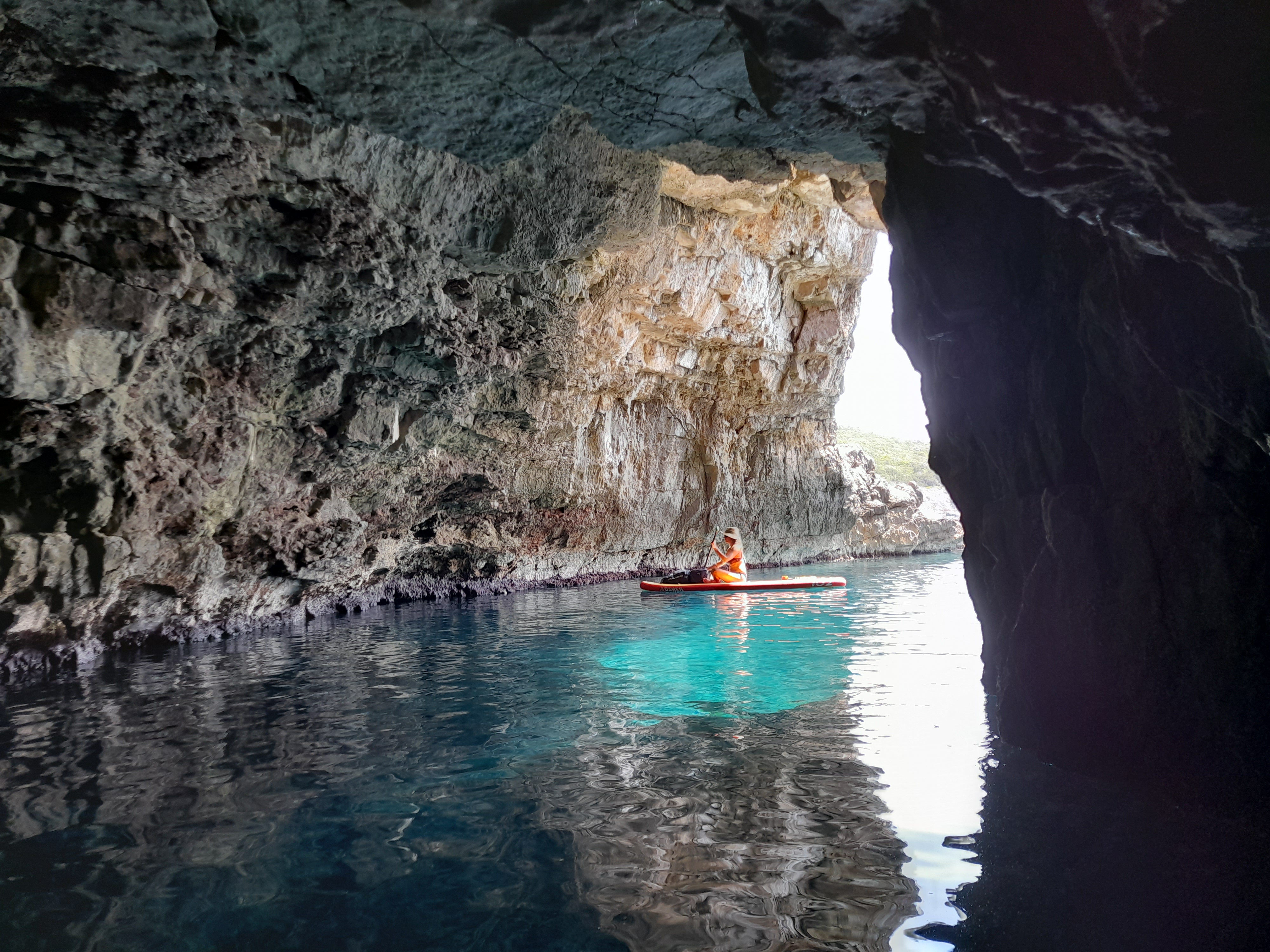 Paddler inside the cave with light streaming through the rock arch