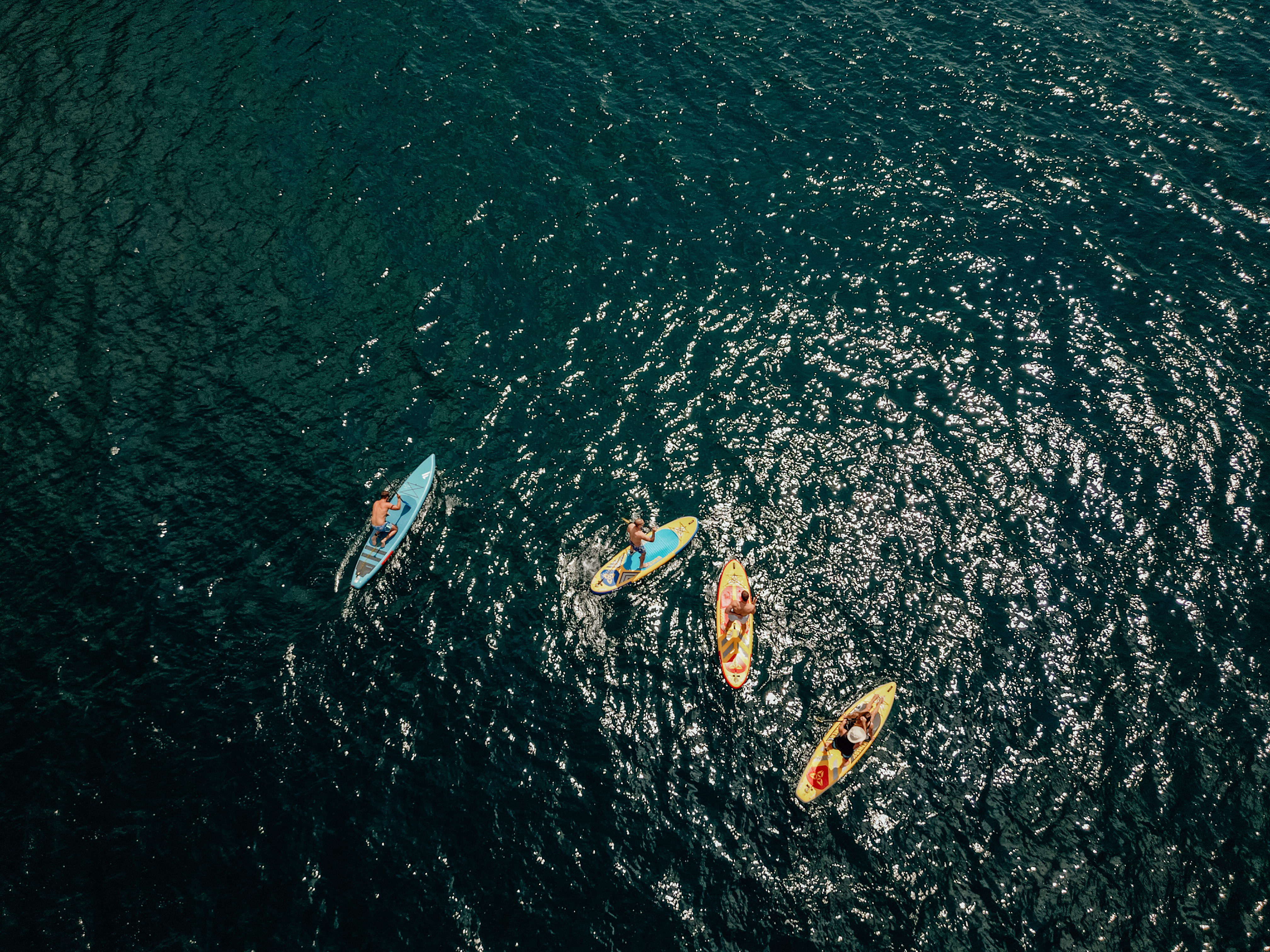 Overhead drone shot of SUP group on sparkling dark water