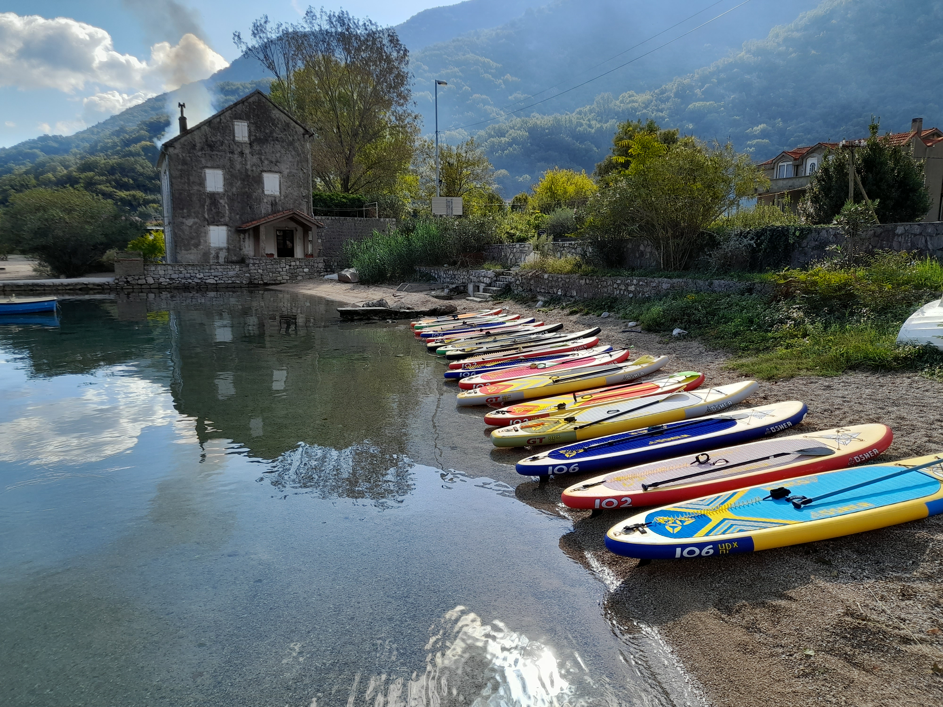 Colourful SUP boards lined up on the shore ready for launch