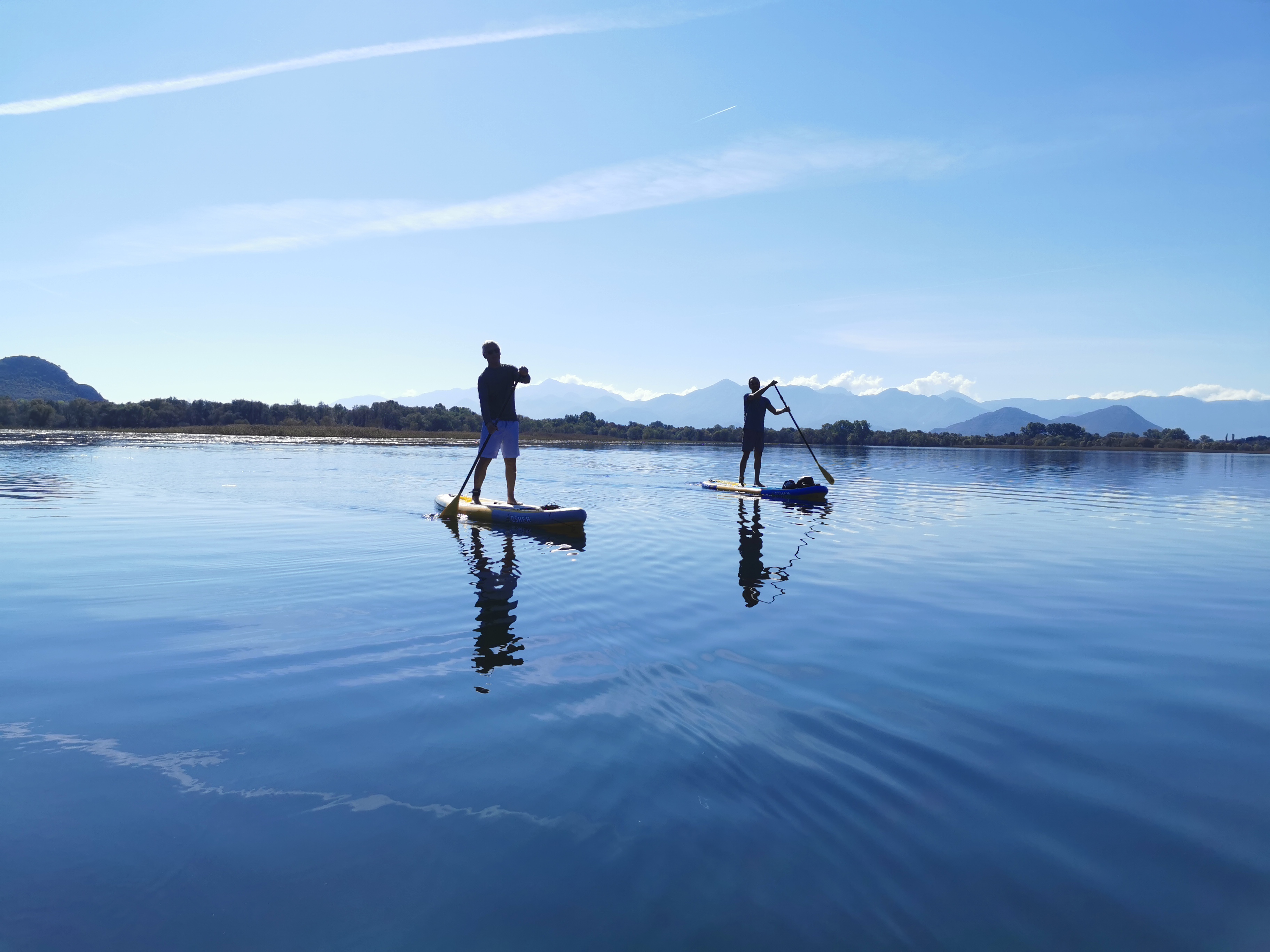 Two paddleboarders on the mirror-calm surface of Skadar Lake