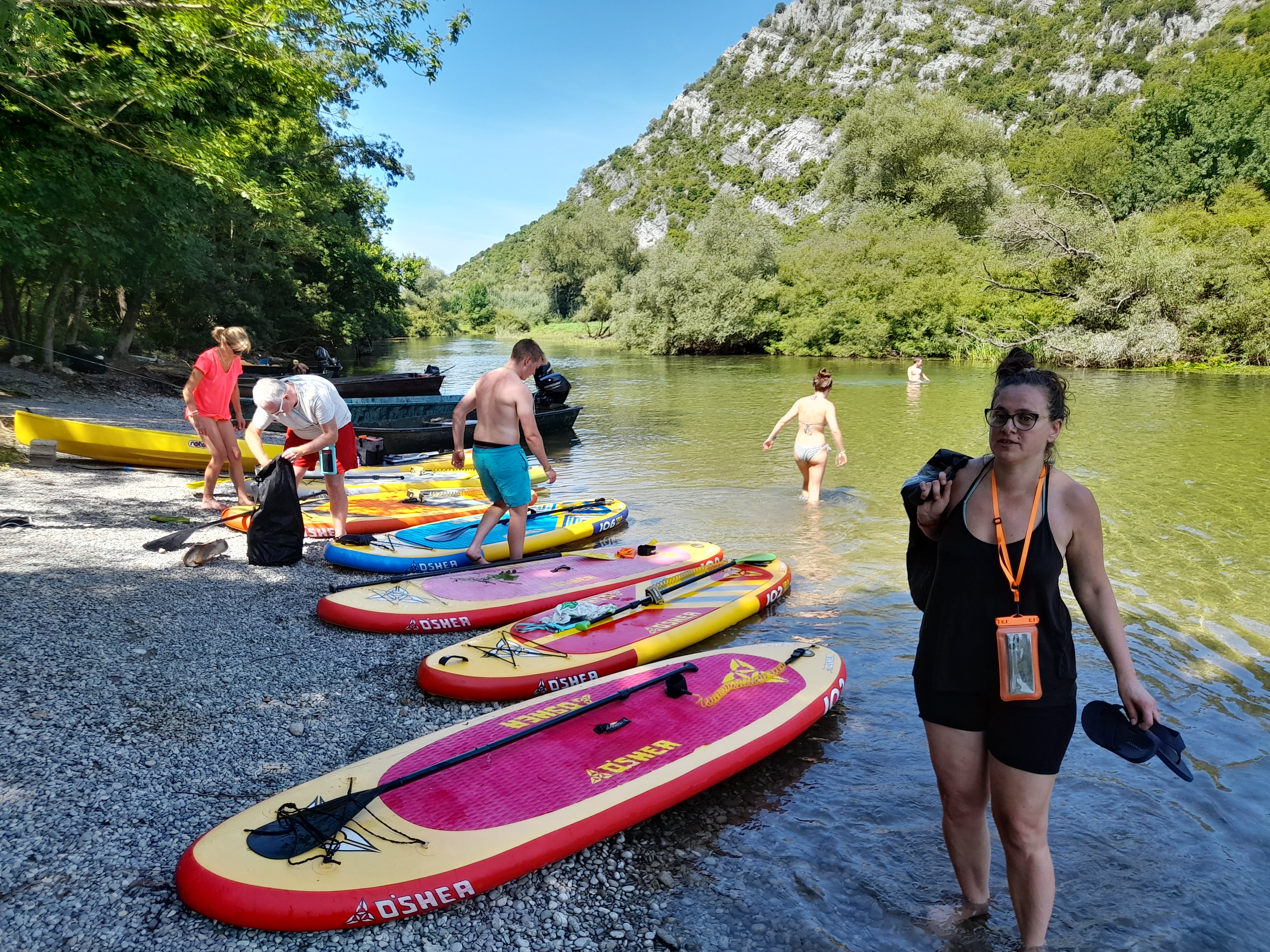 Group preparing SUP boards on the rocky shore of the canyon river