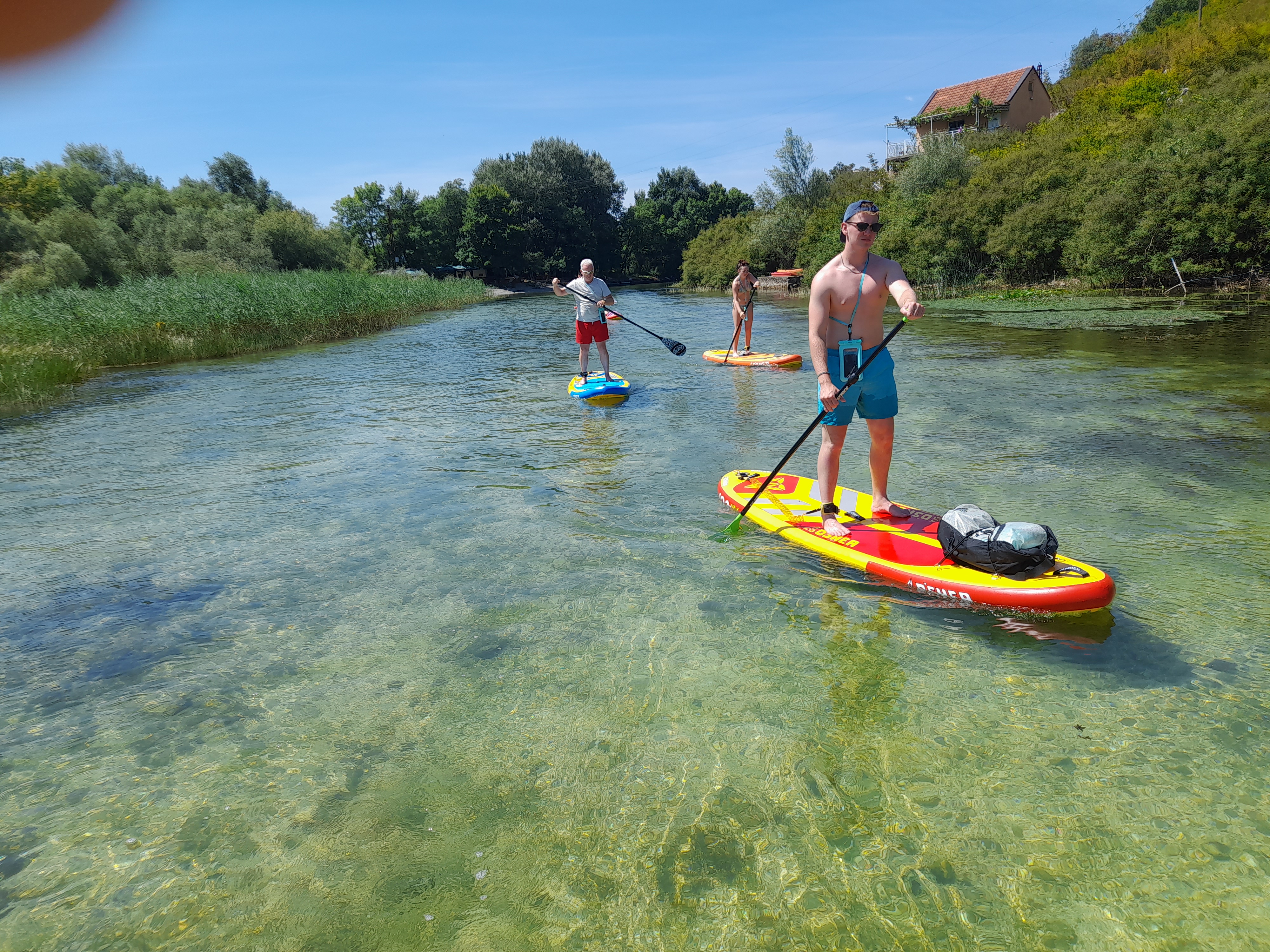 Group paddling through crystal-clear shallow river channel
